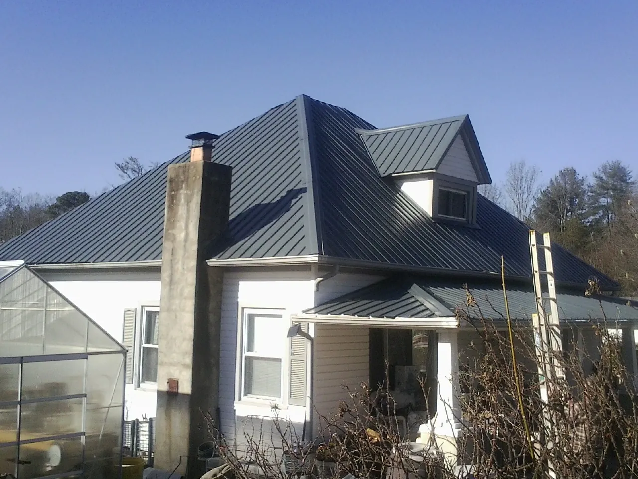 Dark blue standing seam metal roof on a white farmhouse with dormer — Slate & Tile Roof Repair by Roofing Brothers in Fort Mill