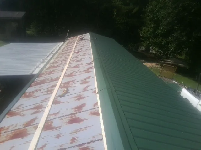 Old rusted panels beside newly installed green metal roofing — Wind Damage Roof Repair by Roofing Brothers in Fort Mill