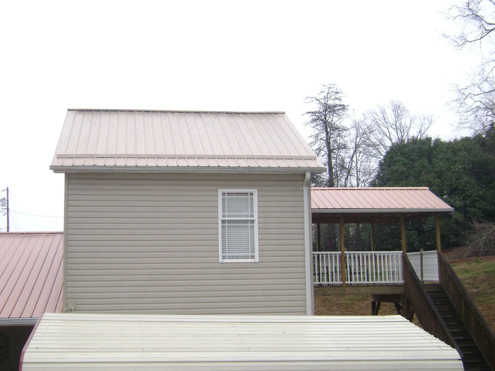 Tan metal roofs on a two story addition and attached porch, from a Roof Replacement job in Fort Mill