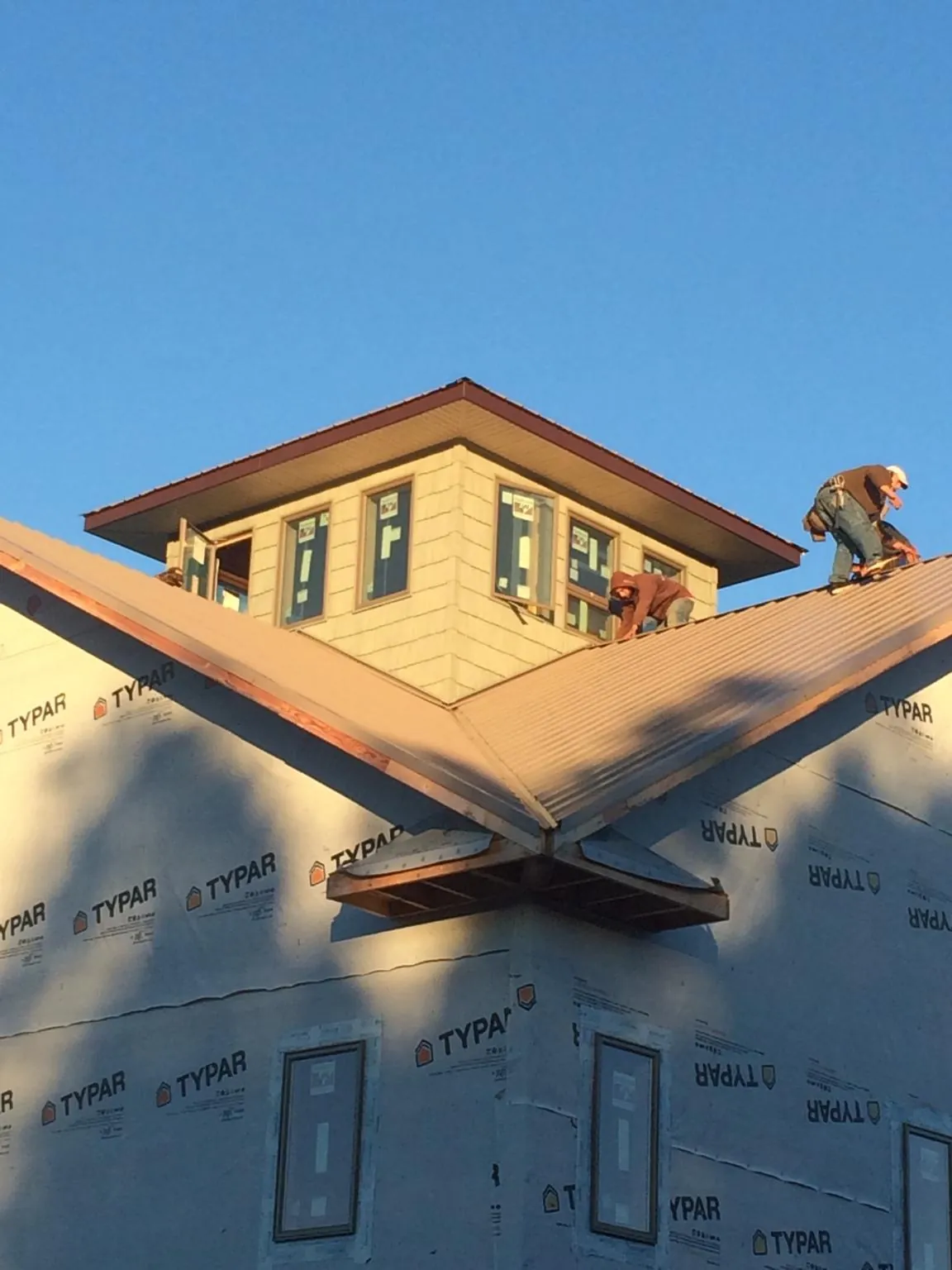 Roofers working around a rooftop cupola on a new metal roof at sunset — Roof Waterproofing in Fort Mill by Roofing Brothers